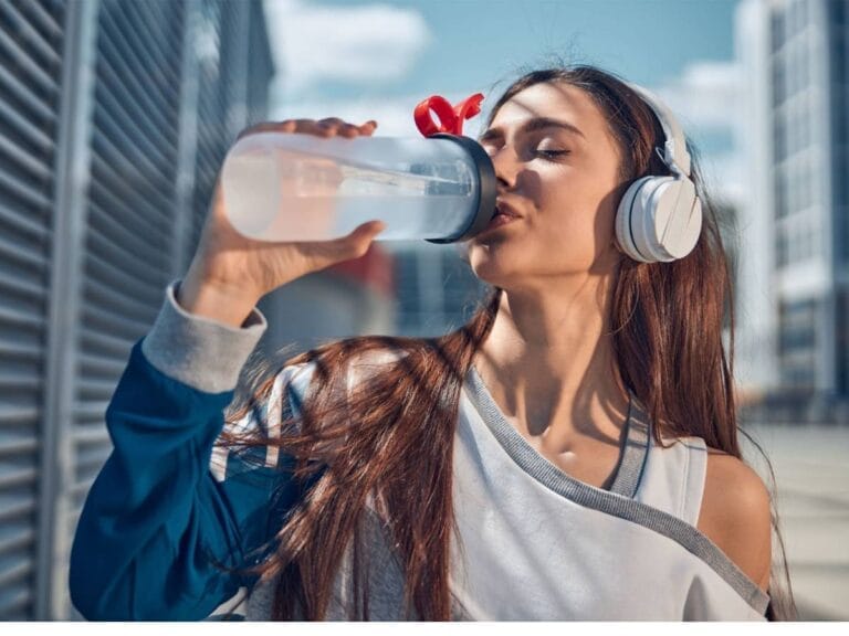 Kobieta w pracy pije wodę Obrazek w artykule Co daje picie wody? Korzyści dla organizmu.