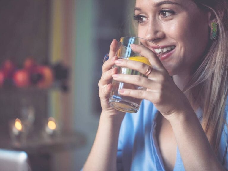 Dziewczyna z kieliszkiem wody. Obrazek w artykule Ile powinno się pić wody dziennie? Poradnik dotyczący codziennej dawki wody